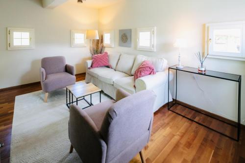 a living room with a white couch and two chairs at Winzerhaus Rose in Wald in der Weststeiermark