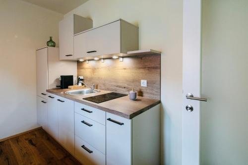 a kitchen with white cabinets and a sink at Winzerhaus Rose in Wald in der Weststeiermark