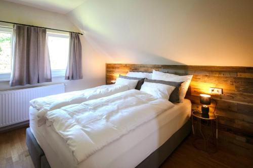 a bedroom with a large white bed with a wooden headboard at Winzerhaus Rose in Wald in der Weststeiermark