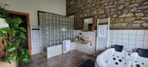 a bathroom with a tub and a stone wall at CASERIO EL AJO in Santillana del Mar