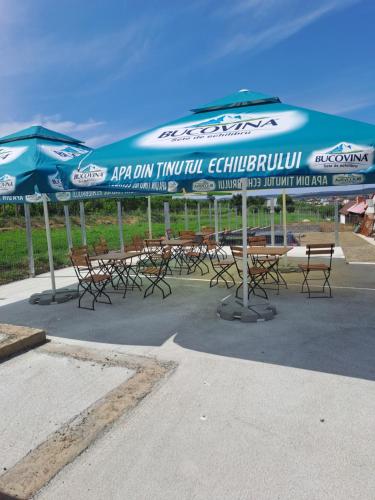 a group of tables and chairs under umbrellas at Pensiunea Raul in Tăşnad