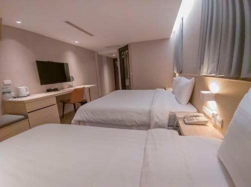 a hotel room with two beds and a desk with a television at Ta Lee Hotel in Tainan