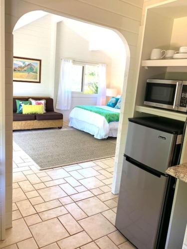 a kitchen with a refrigerator and a bedroom with a bed at North Shore Garden Studio in Haleiwa