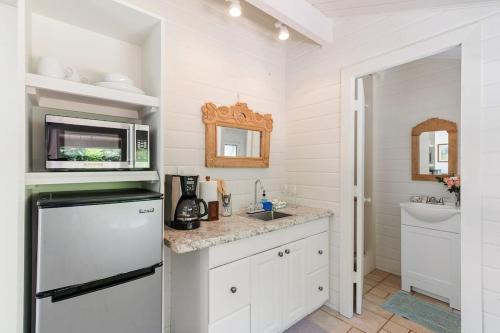 La cuisine blanche est équipée d'un évier et d'un réfrigérateur. dans l'établissement North Shore Garden Studio, à Haleiwa
