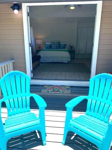 two blue chairs sitting on a porch with a bed at North Shore Garden Studio in Haleiwa