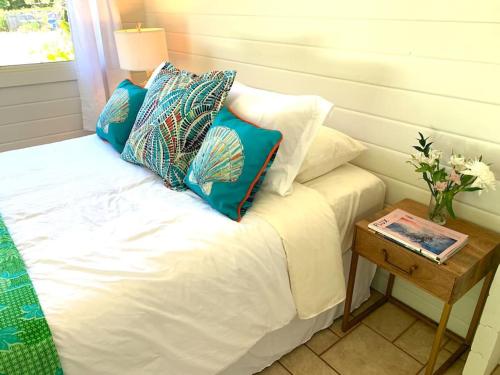 a bed with pillows on it with a side table at North Shore Garden Studio in Haleiwa