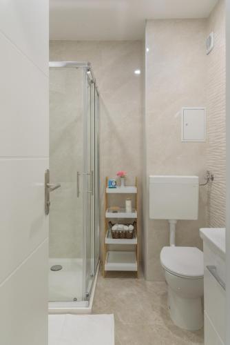 a white bathroom with a shower and a toilet at Apartman Scala in Zadar