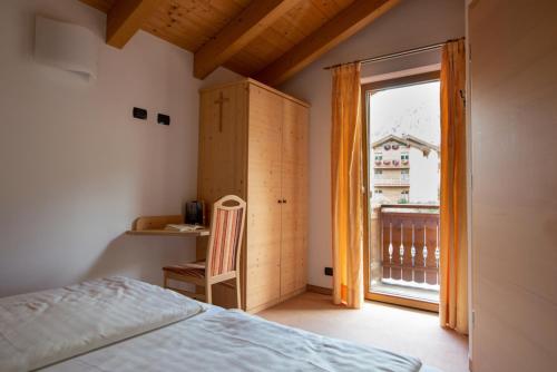 a bedroom with a bed and a window and a chair at Chalet Loredana in Livigno