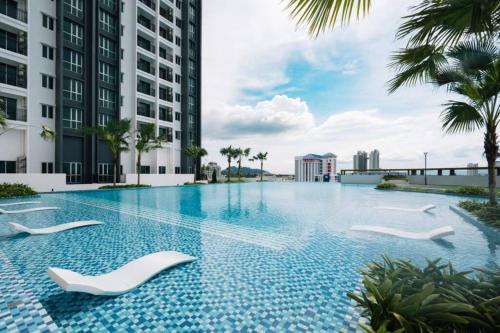 una piscina con sillas blancas frente a un edificio en JOVIAL Modern Cozy Suite `Metropol BM BandarPerda, en Bukit Mertajam