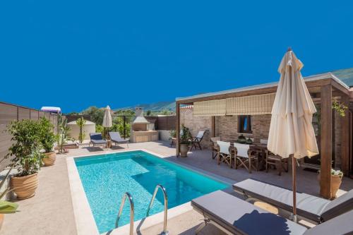 a swimming pool with an umbrella and a house at Villa Frontale - Restored Villa with Pool Perfect for 4 Nestled Next to a Traditional Olive Mill and Local Farms Offering Authentic Hospitality and Organic Delights By Villa Mana Gers in Kallithea