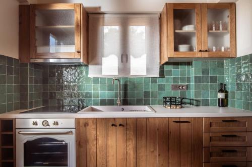 a kitchen with wooden cabinets and green tiles at Villa Frontale in Kallithea