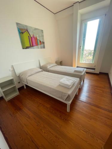 two beds in a room with a wooden floor at APPARTAMENT LONDON PARK in Bordighera