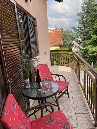uma mesa e cadeiras numa varanda com uma garrafa de vinho em Obiteljska kuća u centru Posušja em Posusje