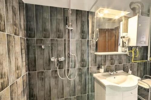 a bathroom with a shower and a sink and a mirror at Velnök Luxus Apartman in Makó