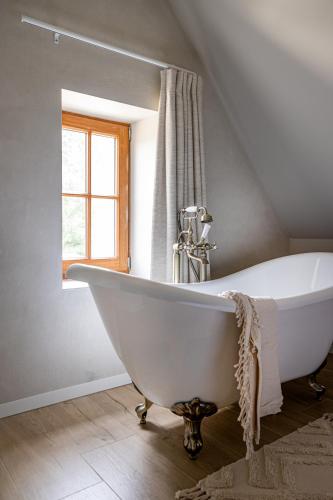 a white bath tub in a bathroom with a window at 't Hooiland in Lo-Reninge
