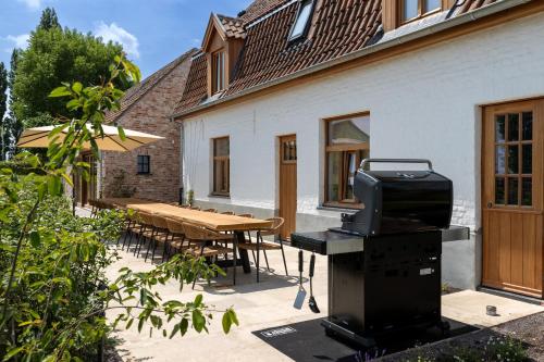 a patio with a table and a bbq grill at 't Hooiland in Lo-Reninge