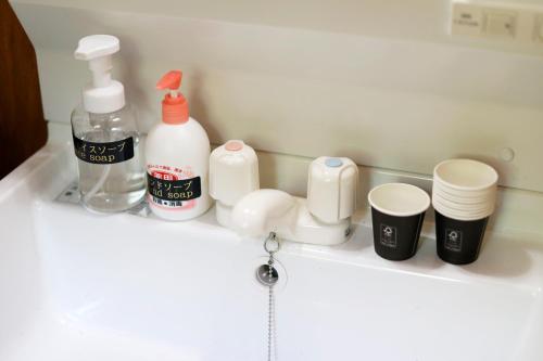 a bathroom sink with bottles and cups on a shelf at The LODGE ABASHIRI in Abashiri