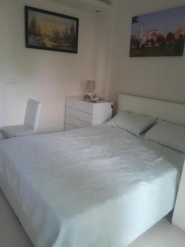 a white bedroom with a white bed and a chair at Konyaaltı Denize Yakın Kiralık Daire in Antalya