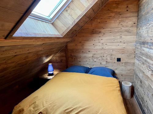 a bed in a wooden room with a window at Chalet Vieux Bois, au coeur du village des Rousses in Les Rousses