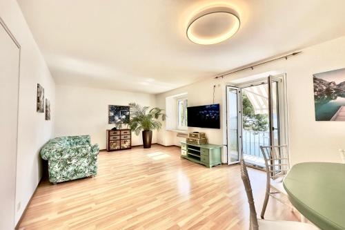 uma sala de estar com uma mesa e uma cadeira e uma televisão em Casa al Lago Apartments - Brissago Experience em Brissago