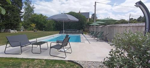 een groep stoelen en een parasol naast een zwembad bij La Varenne in Monthou-sur-Cher