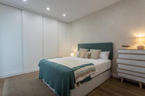a bedroom with a bed with a green headboard and a dresser at Zalaeta Playa Apartments in A Coruña
