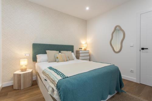 a bedroom with a large bed and a mirror at Zalaeta Playa Apartments in A Coruña