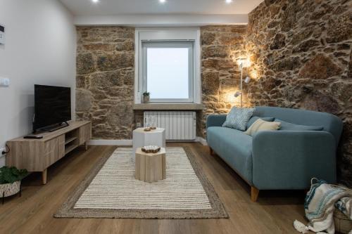 a living room with a blue couch and a tv at Zalaeta Playa Apartments in A Coruña