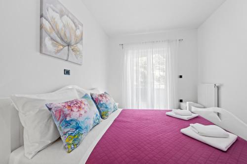 a white bed with a pink blanket and pillows on it at Feniks Fažana apartman in Fažana