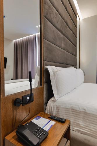 a hotel room with a bed and a desk with a phone at Duka's Hotel in Ksamil