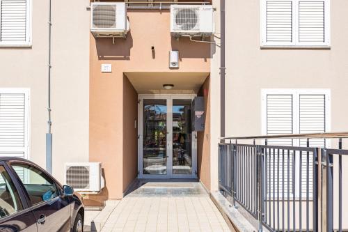a door to a building with a car parked outside at Feniks Fažana apartman in Fažana