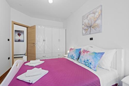 a bedroom with a large bed with a purple blanket at Feniks Fažana apartman in Fažana