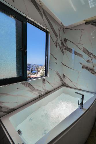 a bathroom with a bath tub with a window at Duka's Hotel in Ksamil