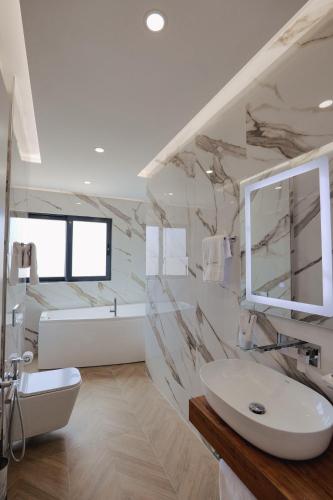 a white bathroom with a sink and a mirror at Duka's Hotel in Ksamil