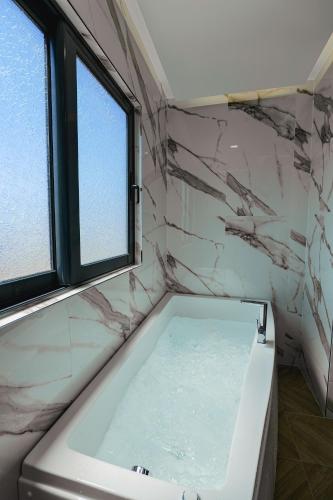 a bathroom with a bath tub with a window at Duka's Hotel in Ksamil