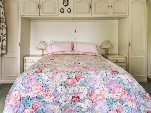 ein Schlafzimmer mit einem großen Bett mit einer Blumenbettdecke in der Unterkunft Woodstock in Chard