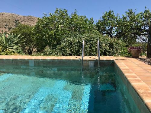 a swimming pool with blue water in a yard at Authentic Sicilian Charm, pool, sea view, wi-fi & parking in Avola