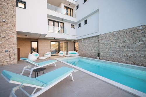 an indoor swimming pool with two blue chairs and a building at Villa Fortunal in Murter