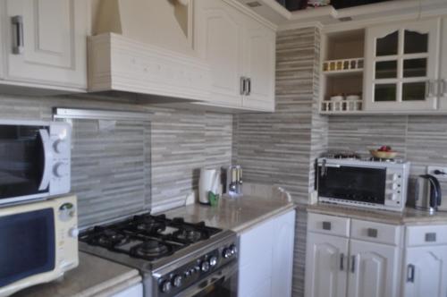 a kitchen with white cabinets and a stove top oven at Spacious Beach Vacation House in El Alamein