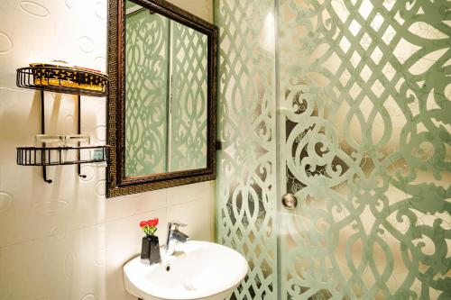 a bathroom with a sink and a mirror and a shower at Wild Lotus Hotel & Travel 2 in Hanoi