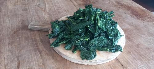 a pile of spinach on top of a wooden table at il larice d' oro in Sueglio