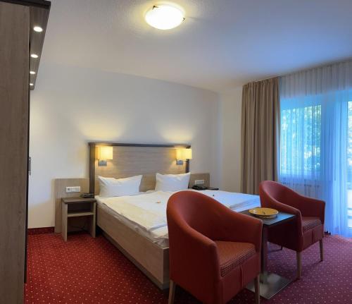 um quarto de hotel com uma cama e duas cadeiras em Kurhotel Haus am Park em Erwitte