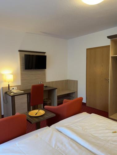 ein Hotelzimmer mit einem Bett und Stühlen sowie einem Schreibtisch in der Unterkunft Kurhotel Haus am Park in Erwitte