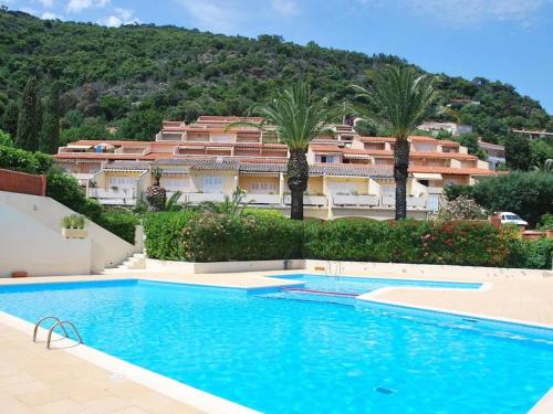 a swimming pool in front of a building with palm trees at Studio Le Lavandou, 1 pièce, 2 personnes - FR-1-308-183 in Le Lavandou