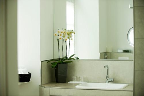 a bathroom with a sink and a vase with flowers at Hotel Residenz am Königsplatz in Speyer