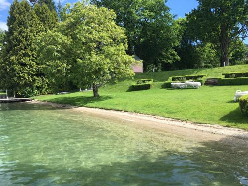 a body of water with a park with trees and benches at See & You Familienwohnung mit Hotelanbindung in Pörtschach am Wörthersee