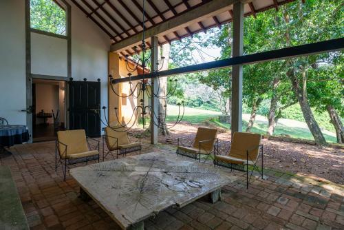 a patio with a table and chairs and windows at Lunuganga Estate in Bentota