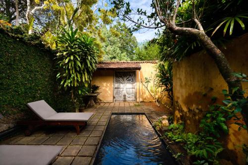 a garden with a pool of water and a chair at Lunuganga Estate in Bentota