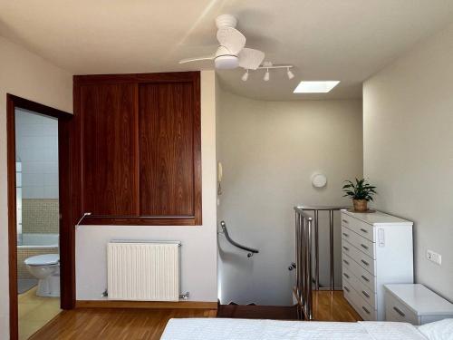 sypialnia z łóżkiem, toaletą i wentylatorem sufitowym w obiekcie Dúplex Calle Cuba Gijón w mieście Gijón