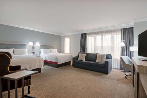 a hotel room with two beds and a couch at Hampton Inn & Suites Stamford in Stamford